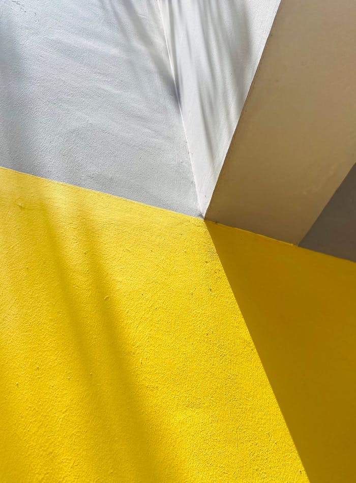 Geometric shadows and vibrant colors on textured cement surfaces creating artistic contrast.
